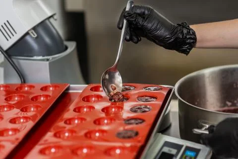 Confectioner in gloves makes chocolates in forms Stock Photos