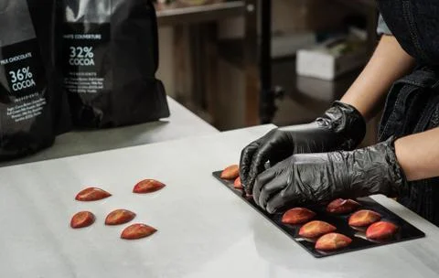 Confectioner in gloves makes chocolates in forms Stock Photos
