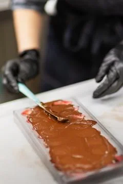 Confectioner in gloves makes chocolates in forms Stock Photos