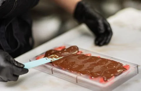 Confectioner in gloves makes chocolates in forms Stock Photos