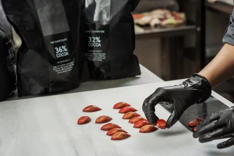 Confectioner in gloves makes chocolates in forms Stock Photos