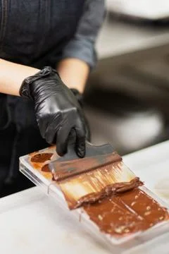 Confectioner in gloves makes chocolates in forms Stock Photos