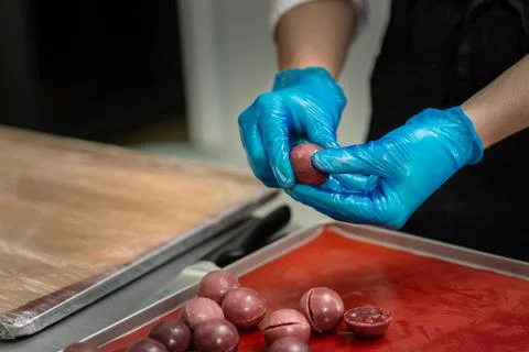 Confectioner in gloves makes chocolates in forms Stock Photos