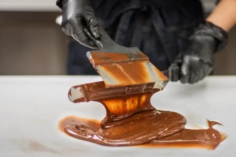 Confectioner in gloves makes chocolates in forms Stock Photos