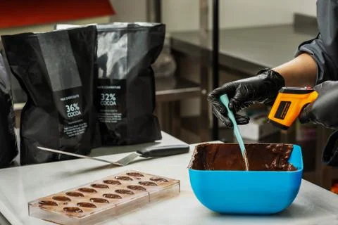 Confectioner in gloves makes chocolates in forms Stock Photos