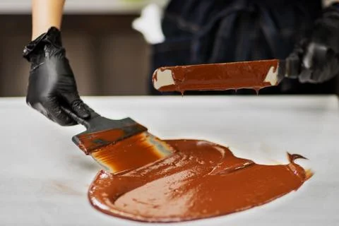 Confectioner in gloves makes chocolates in forms Stock Photos