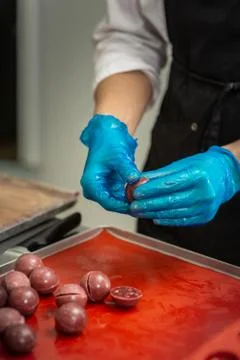 Confectioner in gloves makes chocolates in forms Stock Photos