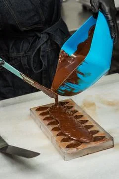 Confectioner in gloves makes chocolates in forms Stock Photos