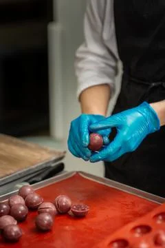 Confectioner in gloves makes chocolates in forms Stock Photos