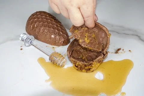 Confectioner holding an Easter egg and showing the filling of a Brazilian hon Stock Photos