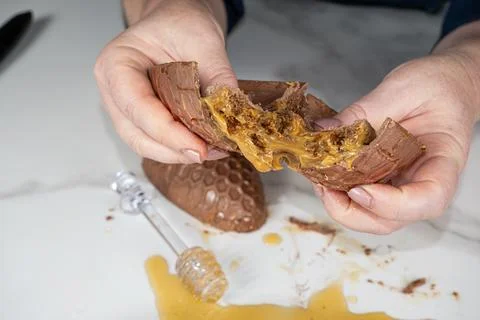 Confectioner holding an Easter egg and showing the filling of a Brazilian hon Stock Photos