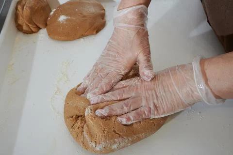 Confectioner in the process of preparing dough, hands in protective gloves in Stock Photos