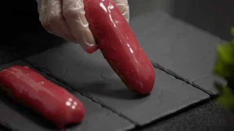 Confectioner put pink glaze eclair on stone plate Stock Footage 95930538