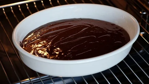 Confectioner puts the form with the dough for chocolate cake into the oven Stock Footage 121109868