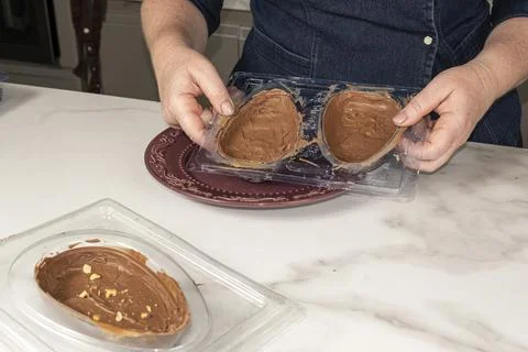 Confectioner ready to remove chocolate Easter egg from the mold. Stock Photos