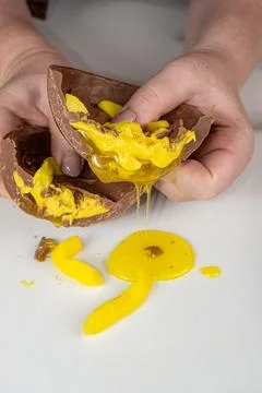 Confectioner showing chocolate Easter egg with banana syrup filling vertical. Stock Photos