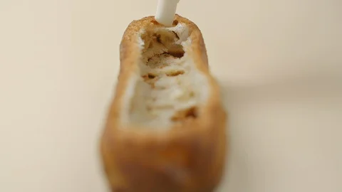 Confectioner is stuffing the eclair with fruit jam and cream, making the sweet Stock Footage 119304231