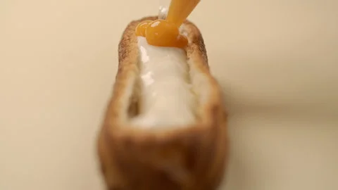 Confectioner is stuffing the eclair with fruit jam and cream Stock Footage 143781993