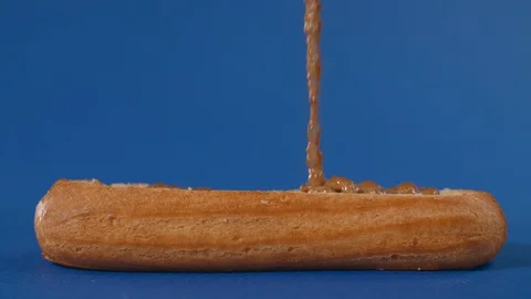 Confectioner is stuffing the eclair with nut butter, making the sweet dessert in Stock Footage 119788287