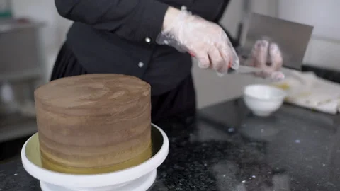Confectioner on table is leveling cake with spatula and cake scraper. Stock Footage 86639829