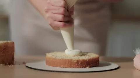 Confectioner topping cake with cream using pastry bag. Woman is cooking homemade Stock Footage 254882566