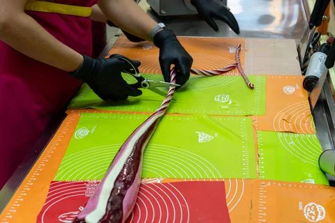 Confectioner Trimming Long Patterned Hard Candy Rope on Work Surface Fotos Stock