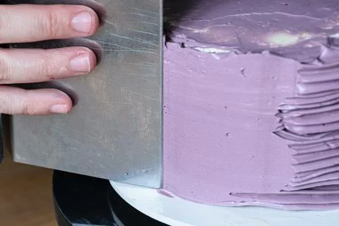 Confectioner using bench scraper to finish the cake. Stock Photos