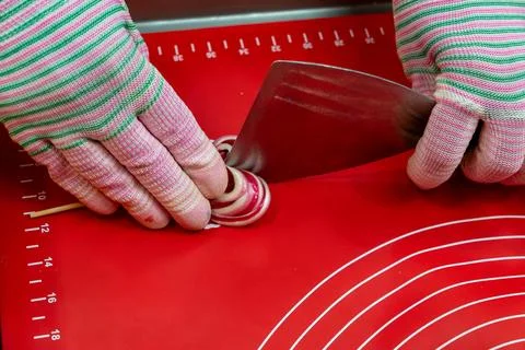 Confectioner Using Metal Scraper Tool to Shape Red and White Swirl Lollipop Fotos Stock