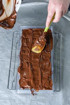 Confectioner using a spatula to place the tempered chocolate in a polycarbona Stock Photos