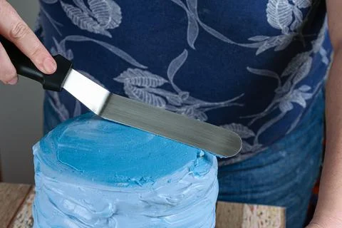 Confectioner using a spatula on top of cake to spread frosting. Stock Photos