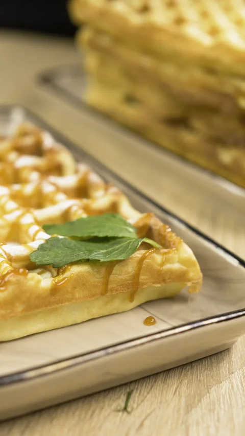 Confectioner working in Bakery. Chef decorated sweet waffles puts mint leaf Stock Footage 319818567