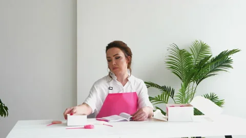 Confectioner writes down the receipe or the order of the sweets in her notebook Stock Footage 152953275