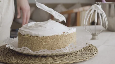 Confectioner's hand finalizing meringue on a sheet cake with a spatula Stock Footage 240113994