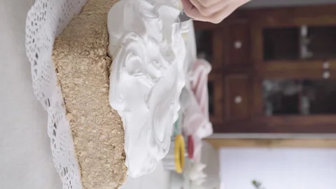Confectioner's hand finalizing meringue on a sheet cake with a spatula Stock Footage 240131185