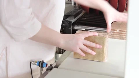 Confectioner's hands pick up packed waffles from a conveyor belt for making Stock Footage 122336340