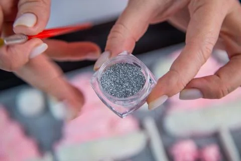 Confectionery silver sequins in an open box is held in the hand of a pastry chef Stock Photos