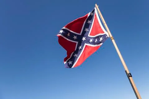 Confederate Flag on pole over blue sky. Stock Photos