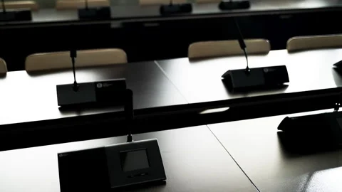Conference microphones sit on long gray tables. Backlight on the microphone 库存影片 248887211