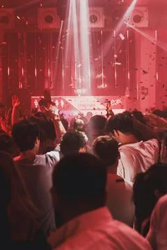 Confetti falling over crowd in red lit club Stock Photos