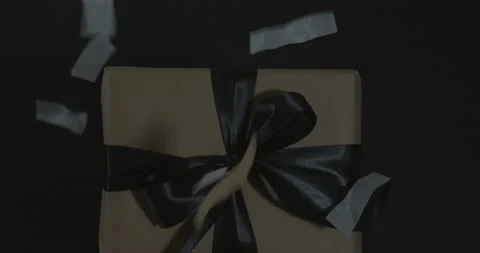Confetti Falls On Wrapped Gift on a Black Background Stock Footage 134420934