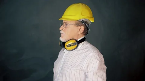 Confidence senior engineer wearing a safety helmet over a grey background Stock Footage 133254905