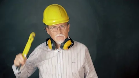 Confidence senior engineer wearing a safety helmet over a grey background Stock Footage 133255245