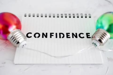 Confidence text on notepad surrounded by colorful light bulbs symbol of ideas Stock Photos