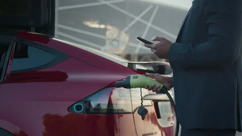 Confident african businessman using modern smartphone, his electric car being Stock Footage 155689823