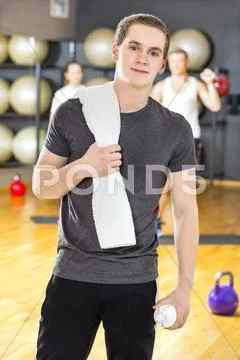 Confident and smiling young man exercising at fitness gym Stock Photos