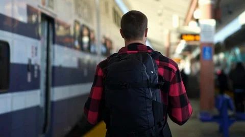 Confident backpacker guy walks by train at Los Angeles Union station.  Video stock 108811303