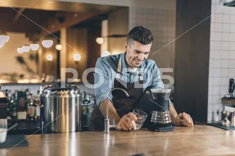 Confident barista looking at the drip decanter with smile Stock Photos