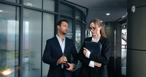 Confident boss gives project feedback to employee in office hallway Stock Footage 320081681