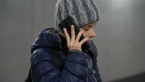 Confident boy in hat and jacket talking on phone in underground covered passage Stock Footage 169229212