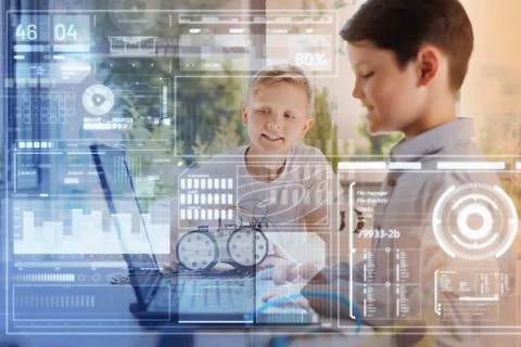 Confident boy working on a laptop while his friend looking at it Foto stock